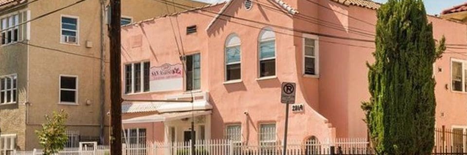 A pink building with a white fence and street sign.