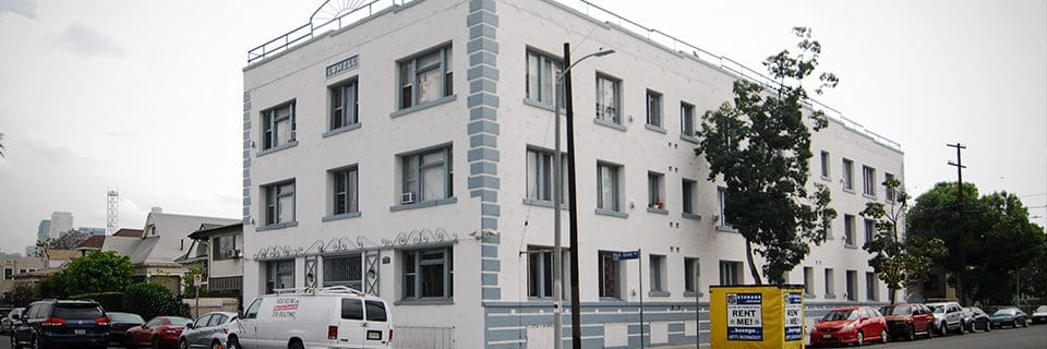 A white building with many windows and a car parked in front of it.