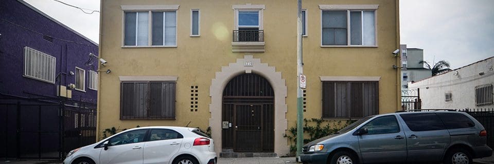 A building with a black door and white car parked in front of it.