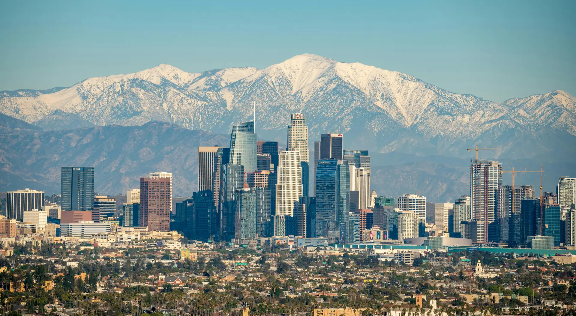 A view of the city skyline with snow capped mountains in the background.